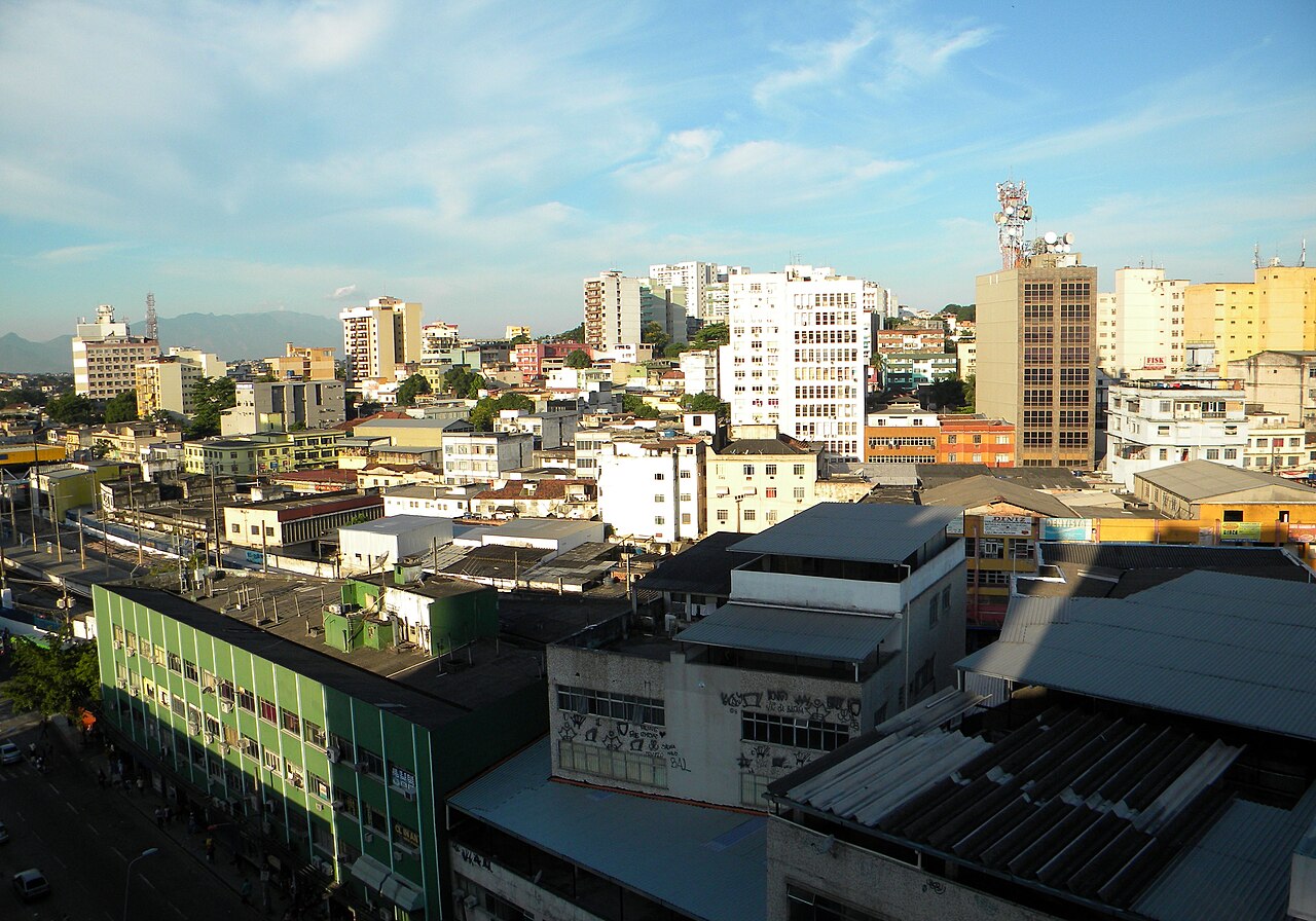Vista elevada do Centro de Duque de Caxias, Rio de Janeiro, com prédios comerciais e residenciais e a serra ao fundo